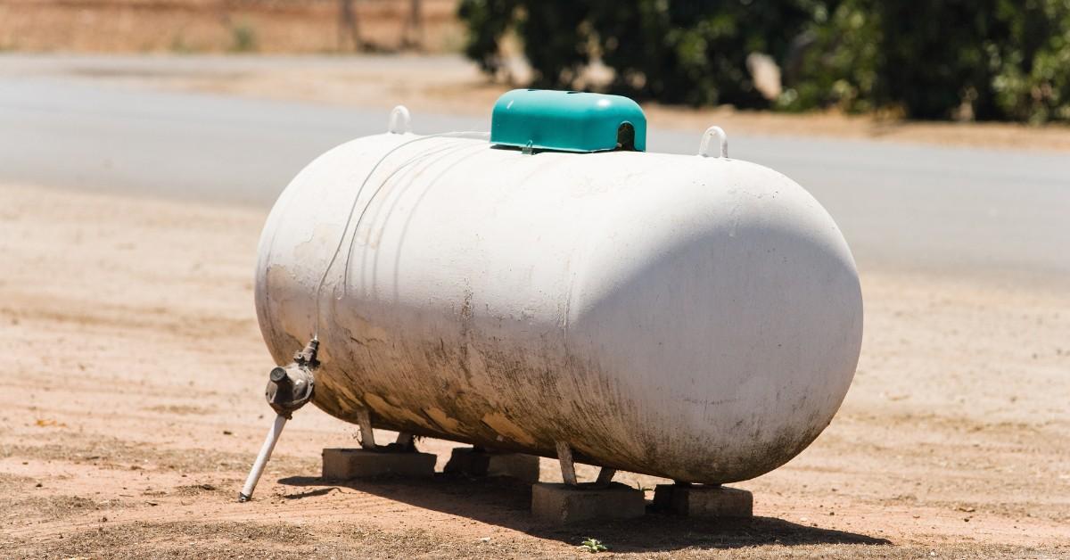 A massive propane tank sits alone next to a road